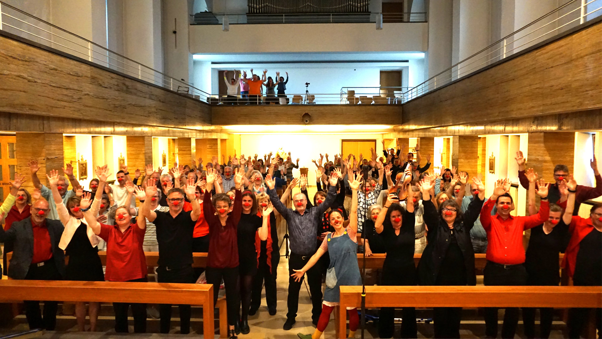 Gruppenfoto von Besuchern, Chor und Band mit KlinikClown "Lotti"